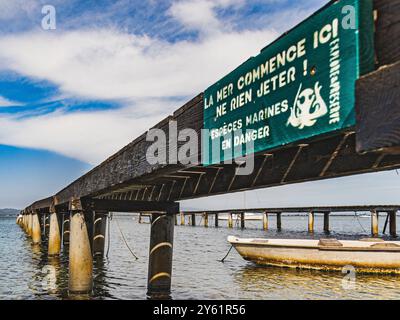 ecological message on the pollution of the seas and oceans, boat floating on the sea near a pontoon Stock Photo