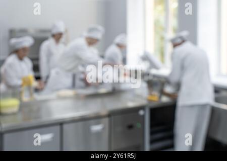 A team of chefs working in a kitchen, a blurry image of a culinary production or bakery. High quality photo Stock Photo