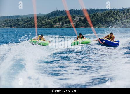 Friends enjoying summer speedboat tubing adventure on the open sea Stock Photo