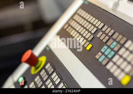 Control panel of cnc turning milling lathe machine at factory, plant, red emergency switch button on foreground - close up side view. Panel with butto Stock Photo