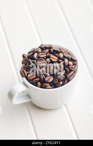 Roasted coffee beans in coffee cup on a white table. Stock Photo