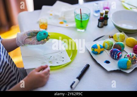 Child decorating Easter eggs with bright colors and designs during creative art session at home. Sweden. Stock Photo