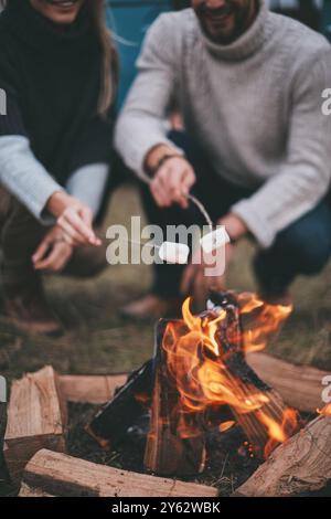 Romantic night.  Close up of young couple roasting marshmallows over a campfire while enjoying their road travel Stock Photo