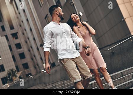 Couple on the go. Beautiful young couple holding hands and smiling while walking outdoors Stock Photo