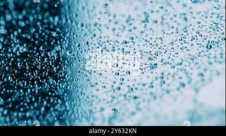 Macro photography showing tiny bubbles floating in blue liquid, creating an abstract background with a refreshing feel. Stock Photo