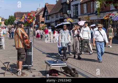 Stratford Upon Avon - United Kingdom; July 28 2024; people walking by busker in typical busy English city street on summer weekend Stock Photo