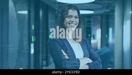 Smiling woman with crossed arms over programming code image in office environment Stock Photo