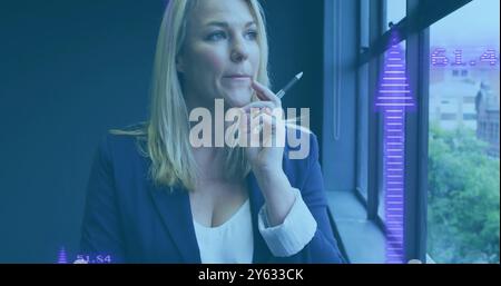 Holding pen and thinking, woman with data visualization image over her face Stock Photo