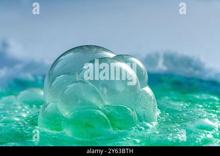 A green, aqua frozen soap bubble showing textured icy, ice covered surface on a 40 below day in northern Canada during winter season. Stock Photo