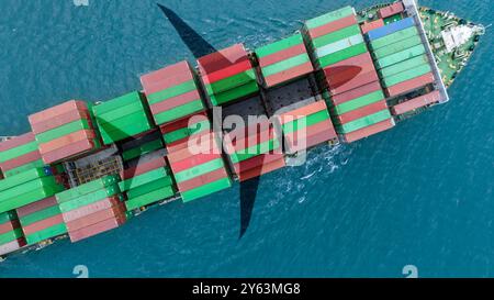 Aerial view container cargo ship at sea with airplane shadow. Global trade and logistics concept. Maritime freight transportation and environmental Stock Photo