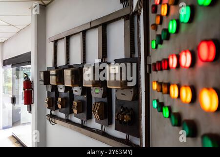 Old kWh meter circuit arrangement with old and rustic electrical control panel with red, green, and yellow lights inside a building Stock Photo