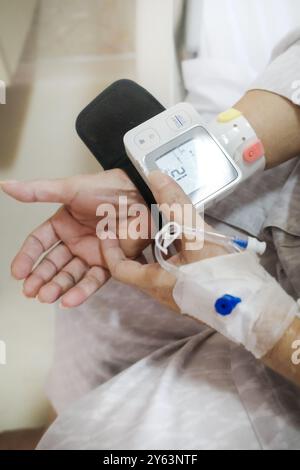 Mature adult female patient using digital blood pressure and heart rate measuring device on her wrist Stock Photo