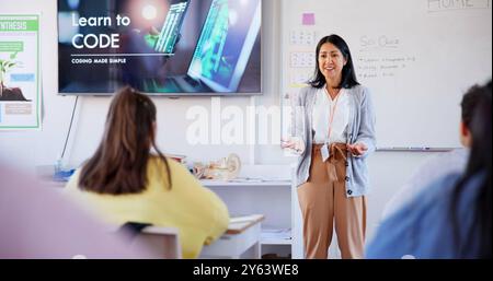 Education, teacher and students with presentation in classroom for introduction to coding and learning. Woman, kids and happy with lesson, studying Stock Photo