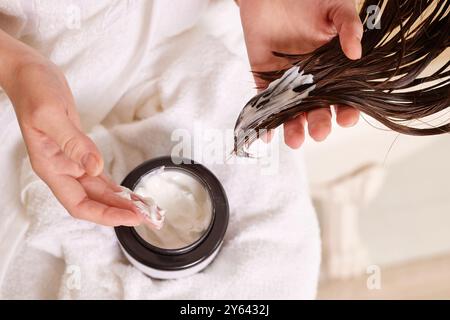 Person applying hair mask to wet hair, close-up of hands and hair. Stock Photo