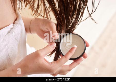 Person applying hair mask to wet hair, close-up of hands and hair. Stock Photo
