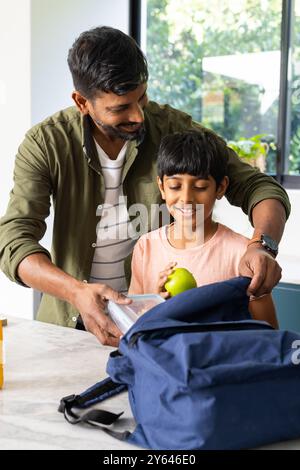 Packing school backpack, indian father helping son with lunch and books, smiling together Stock Photo