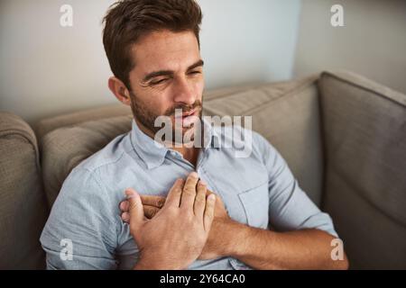 Man, chest pain and heart attack with stress on sofa for medical emergency, discomfort and cardiac arrest. Professional, person and cardiovascular Stock Photo