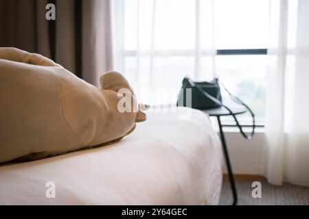 Hotel room with soft toy on top of bed and woman's handbag on top of coffee table. Stock Photo