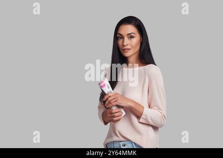 Simply stunning. Studio shot of attractive young woman in casual looking at camera with smile while standing against grey background Stock Photo