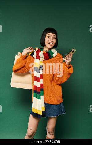 A young woman with short hair and tattoos smiles joyfully, dressed in a cozy sweater and colorful scarf. Stock Photo