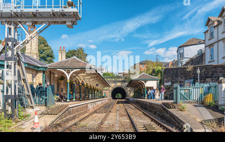 Two railway station canopies supported by green columns are aside the entrance to a tunnel. Rails lead into the tunnel and the a sky with cloud is abo Stock Photo