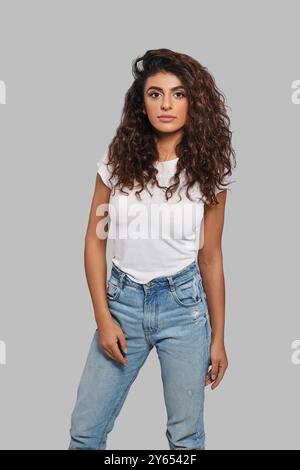 Simply stunning. Attractive young woman looking at camera while standing against grey background Stock Photo