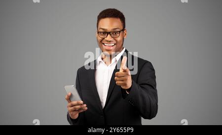 African american guy with phone pointing at you Stock Photo