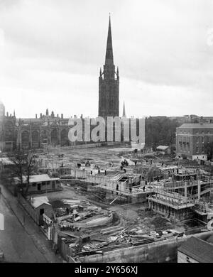 The spire and bomb torn fabric of the old Coventry Cathedral , devastated during wartime Blitz attacks on the city , looms over construction work on the new cathedral . In the foreground is the foundations of the circular Guild Chapel , and beyond can be seen the nave floor . On March 23rd the Queen is to visit Coventry to lay the foundation stone of the new cathedral and the Chapel of Unity . She will be accompanied by the Duke of Edinburgh , Coventry , Warwickshire , England . March 1956 Stock Photo