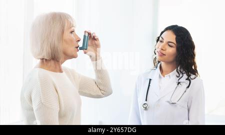 Physician examining mature woman using blue asthma inhaler Stock Photo