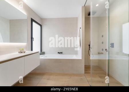 With a sleek and modern design, the bathroom of this luxurious Mediterranean villa features a large bathtub, a glass shower and a minimalist vanity un Stock Photo
