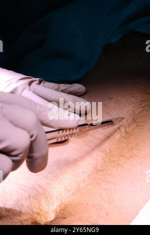 A close-up image capturing a surgical procedure, showcasing a surgeon's hands using surgical tools on a patient under the bright light of an operating Stock Photo