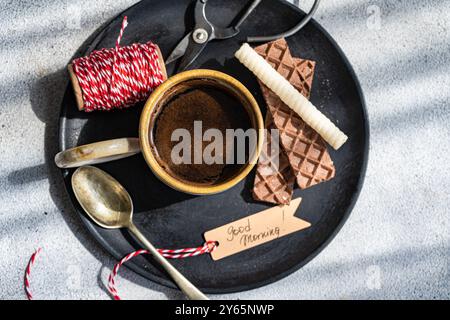 Top view of a casual morning coffee scene featuring a ceramic cup of black coffee, flanked by chocolate bars and a textured waffle, all presented on a Stock Photo