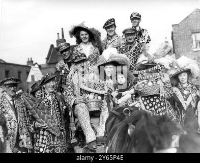 Costermongers flock to ' Pearlies ' own harvest festival . - - By donkey carts and on foot , dressed in their pearls and feathers the pearly kings and queens flocked to their own Harvest Festival service at St Mary Magdelene ' s Church off the Old Kent Road , London , bearing their offerings of fruit , vegetables and loaves . - - 11th October 1948 Stock Photo