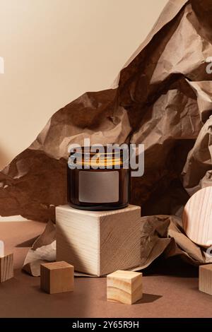 A serene setup featuring an elegant candle in a dark glass jar, neatly placed on a stark wooden pedestal The background consists of wrinkled brown pap Stock Photo