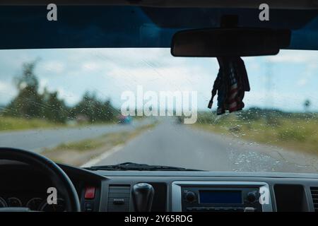 Inside view of a car journeying on a wet road under a rain-swept windshield, with the lush landscape of Vinales Valley, Pinar del Rio, Cuba, ahead, hi Stock Photo