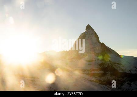 A breathtaking winter sunrise illuminates a snow-covered mountain peak, casting vibrant hues and creating a serene, frosty landscape ideal for skiing Stock Photo