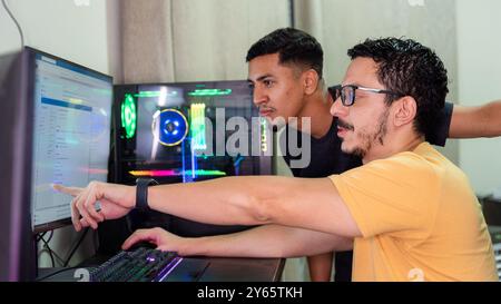 A gay couple engaging with software on a computer screen, illustrating a moment of collaboration in a vibrant tech environment The setting includes ad Stock Photo