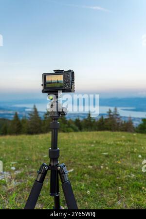 A camera mounted on a tripod captures a stunning panorama of Lake Leman, the French and Swiss Alps from La Barillette, contrasting with a vibrant, clo Stock Photo