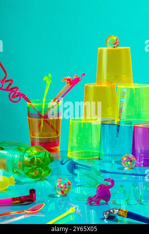 An upbeat arrangement of colorful party items, including plastic cups, straws, and decorations, set against a turquoise backdrop This playful setup ex Stock Photo