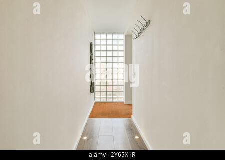 Minimalist hallway with a glass block window and a coat rack on the wall. Stock Photo