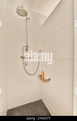 A pristine modern shower with a large shower head, metallic fixtures, and neatly tiled walls in a bright bathroom setting. Stock Photo