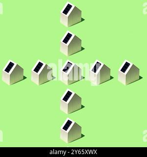 Aerial view of miniature houses equipped with solar panels on their roofs, arranged in a geometric pattern on a green surface This image represents su Stock Photo