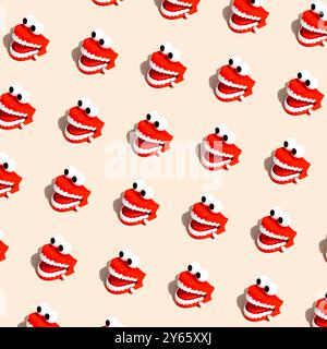 A whimsical pattern of red and white chattering teeth toys scattered on a beige studio background. Stock Photo