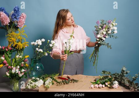 female florist makes a bouquet in a flower shop, spring bouquet Stock Photo