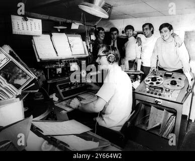 Disc jockeys of the pirate radio ship Radio Caroline North pictured in the studio of the vessel yesterday    Left to right in rear  Dee Harrison Don Allen Wally Mechan Madic Sloane Jimmy Gordon and Martin King is seated    Radio Caroline is anchored four miles off Ramsey Isle of Man and Mr Ronan O’Rahilly 27 the owner said the ship is there to stay 1967 Stock Photo