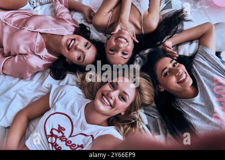 Portrait of four young women lying on the bed smiling Stock Photo - Alamy