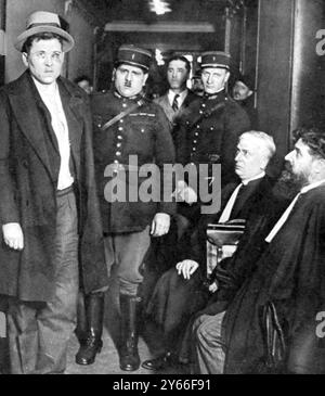 The Murder of President Doumer: scenes after the crime. The assassin at a police station Paul Gorguloff, in custody of two police officers being interrogated by authorities of whom he is said to have made a very incoherent statesmen May 1932 Stock Photo