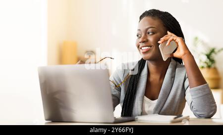 Young Black Businesswoman Talking On Cellphone While Working In Office Stock Photo