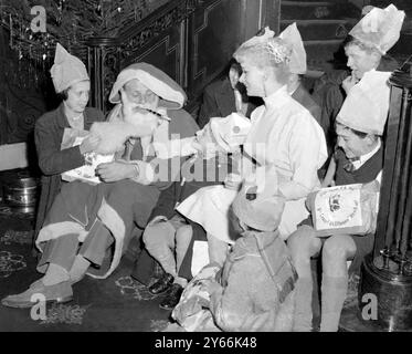 Two of the stars of the film - Sabrina and Terry Thomas, in Father Christmas costume, distribute presents to some of the orphan children who saw the film this morning 21 December 1957 Stock Photo