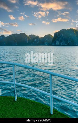 original view of Ha Long Bay in Vietnam taken from the bow of a boat sailing in the archipelago, a landmark tourist spot at sunset Stock Photo